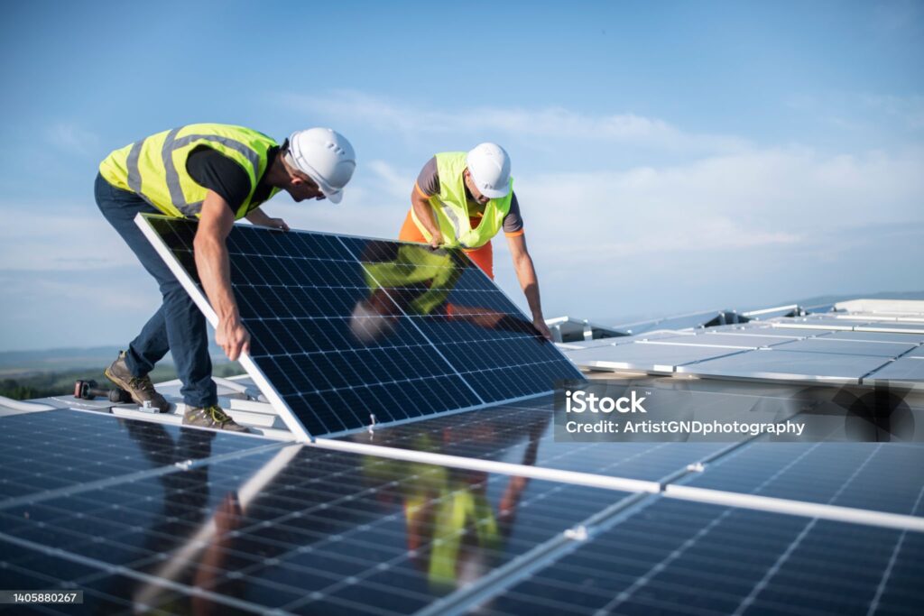 Team of two engineers installing solar panels on roof.